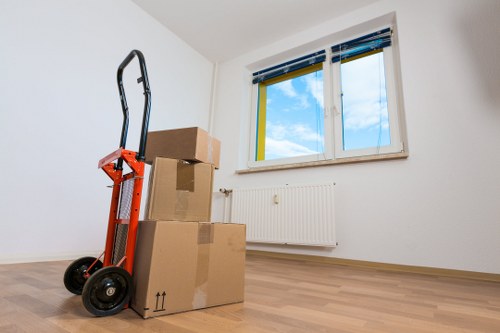 Local movers carrying boxes down stairs in an Islington property